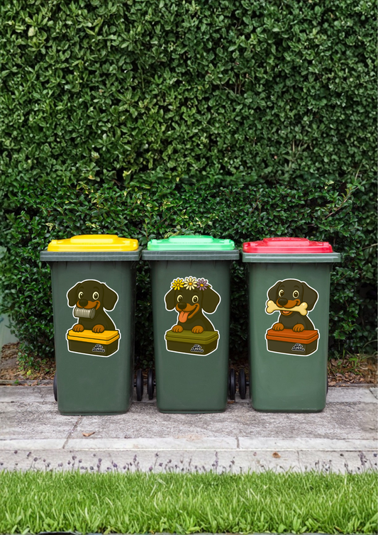 Three wheelie bins with dog stickers on a grassy background.