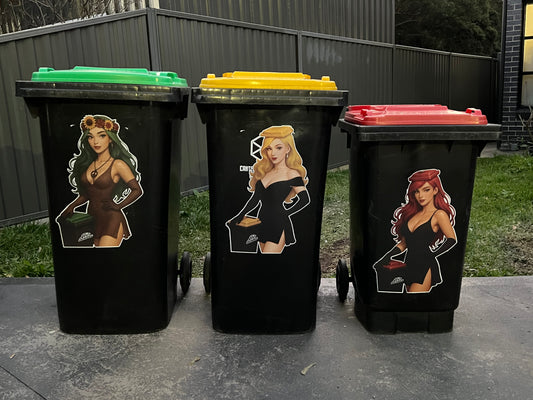 Three black trash bins with colorful lids and artistic designs on a concrete surface.