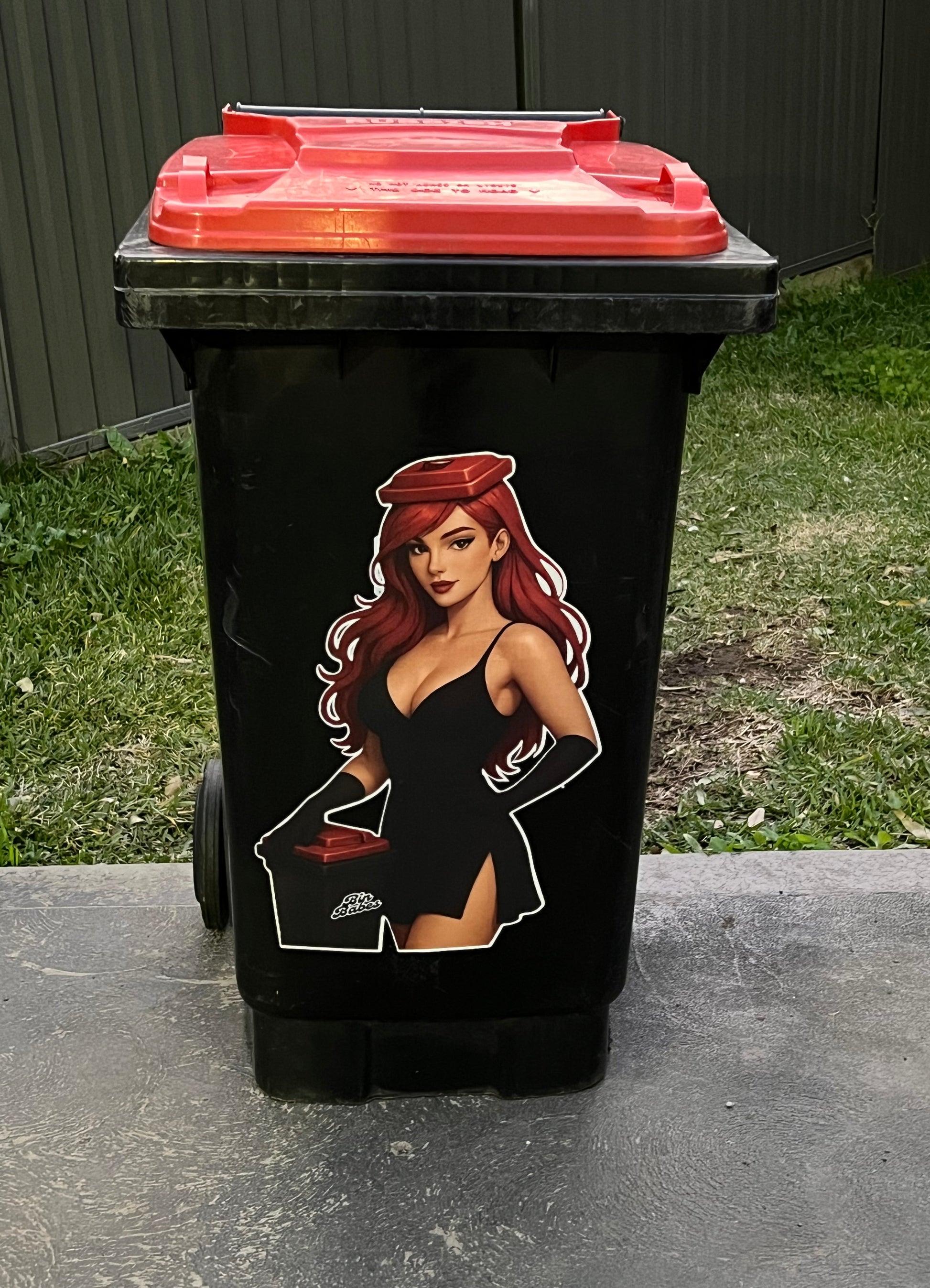 Black trash bin with a graphic design of a woman on a grassy and concrete surface