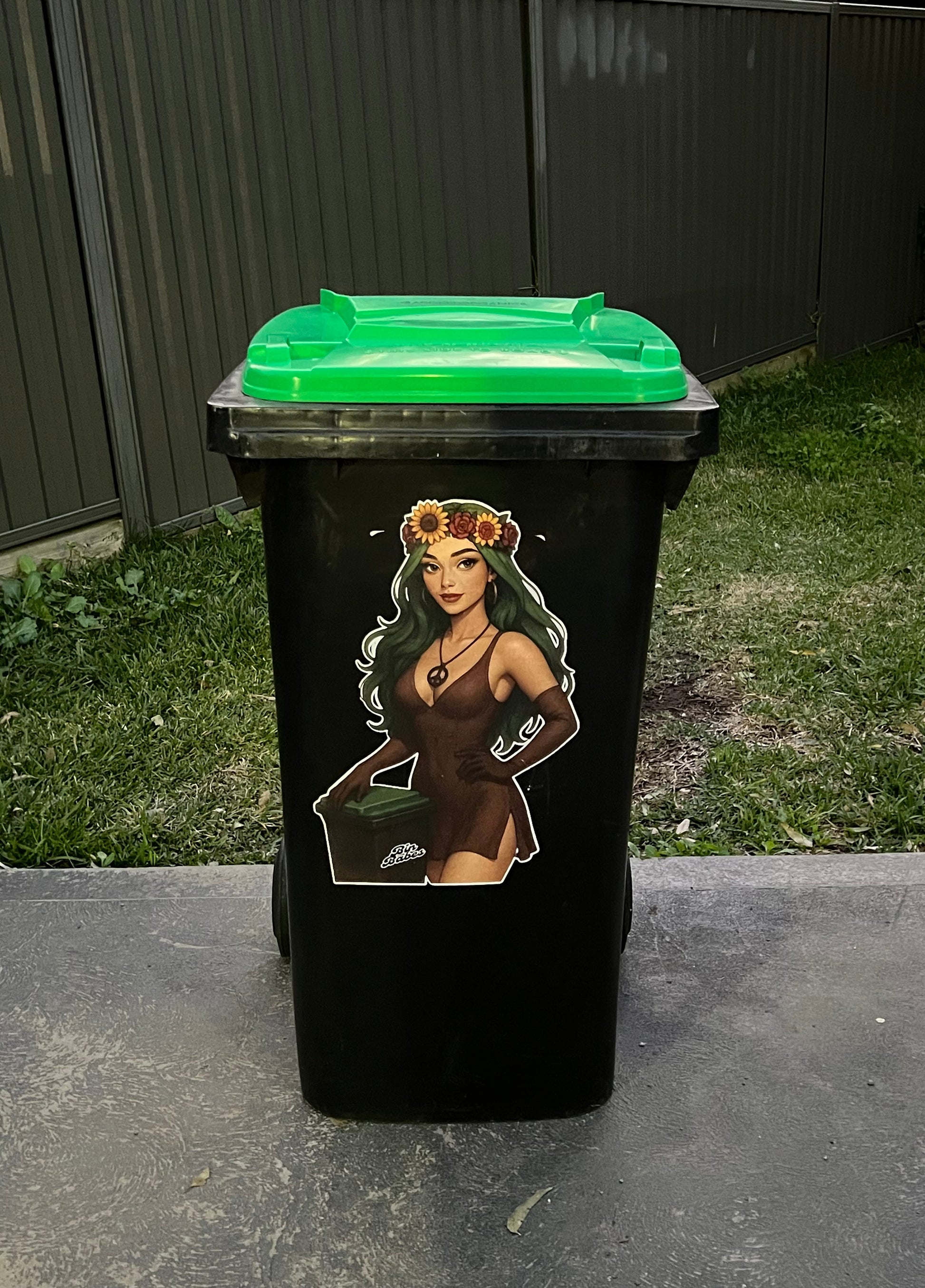 Black trash bin with a green lid on a concrete surface